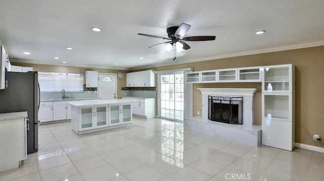 kitchen featuring sink, a kitchen island, stainless steel fridge, decorative backsplash, and white cabinets