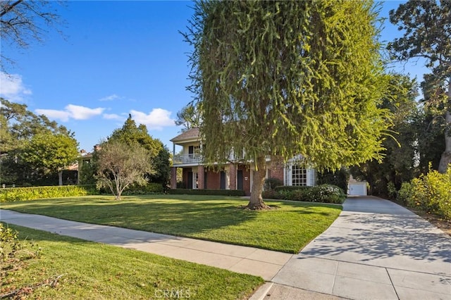 view of property hidden behind natural elements featuring a balcony, a garage, and a front lawn