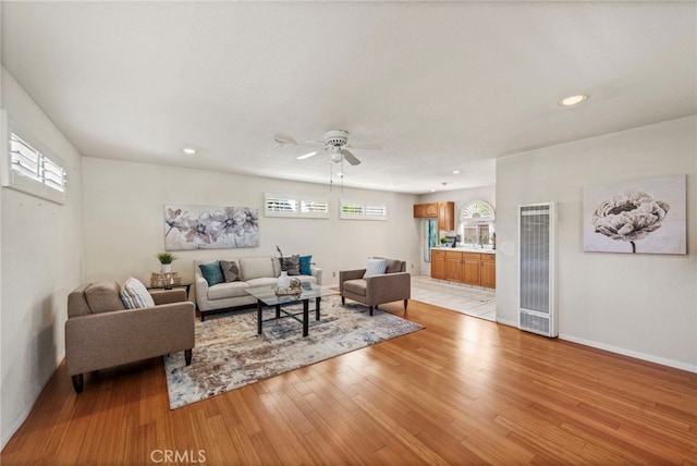 living room with light hardwood / wood-style floors, ceiling fan, and a healthy amount of sunlight