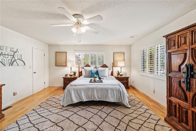 bedroom with multiple windows, hardwood / wood-style floors, a textured ceiling, and ceiling fan