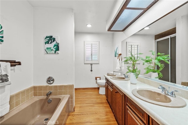 bathroom featuring hardwood / wood-style floors, vanity, a tub to relax in, and toilet