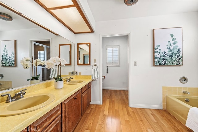 bathroom with vanity, hardwood / wood-style flooring, a wealth of natural light, and a bathing tub