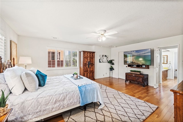 bedroom with hardwood / wood-style floors, ceiling fan, a textured ceiling, and ensuite bath