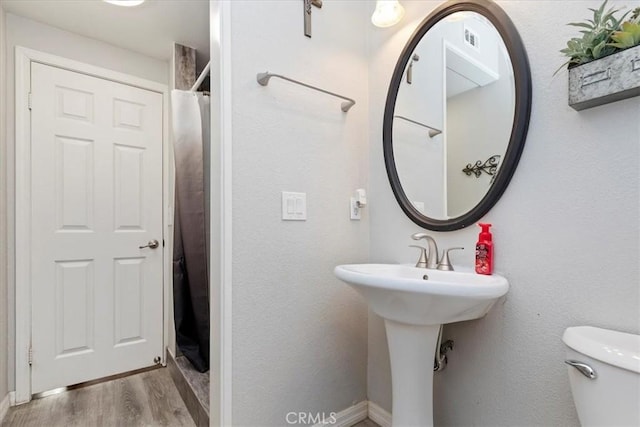 bathroom with hardwood / wood-style floors, a shower with shower curtain, and toilet