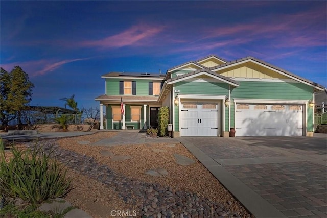 view of front of home featuring solar panels, a garage, and a porch