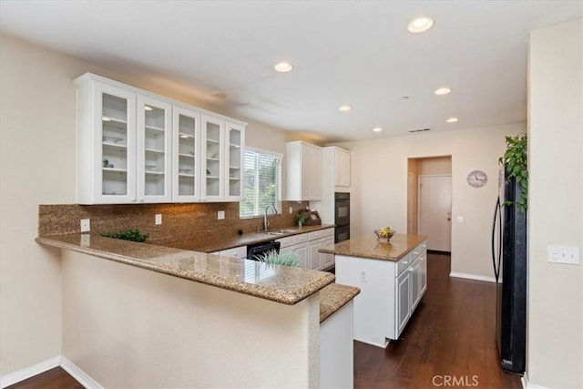 kitchen featuring sink, kitchen peninsula, a kitchen island, light stone counters, and white cabinetry