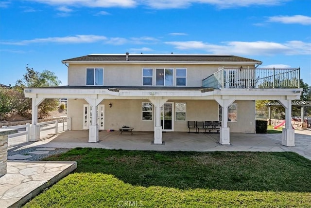 rear view of house featuring a balcony, a yard, and a patio