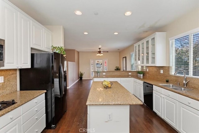 kitchen with a center island, black appliances, white cabinets, sink, and decorative backsplash