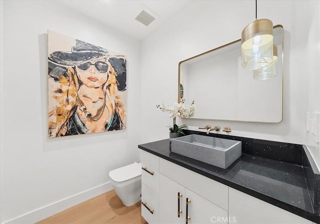 bathroom featuring vanity, wood-type flooring, and toilet