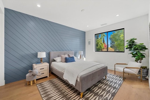 bedroom featuring hardwood / wood-style floors and wood walls