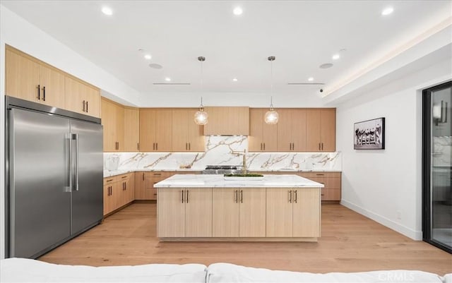 kitchen with a kitchen island, stainless steel built in refrigerator, hanging light fixtures, and light brown cabinets