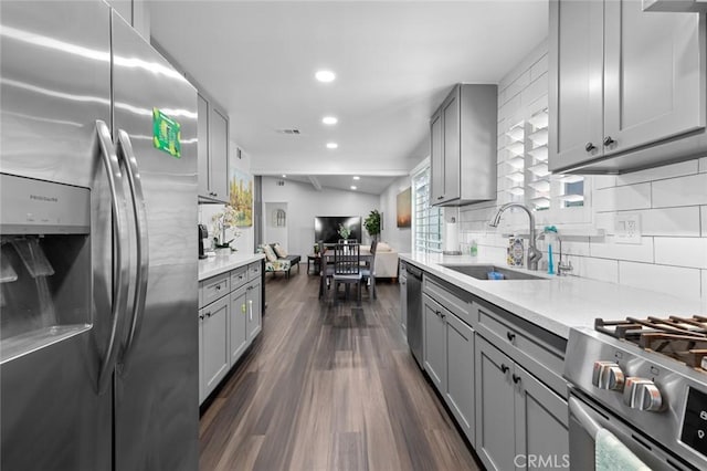 kitchen featuring decorative backsplash, gray cabinetry, stainless steel appliances, sink, and dark hardwood / wood-style floors