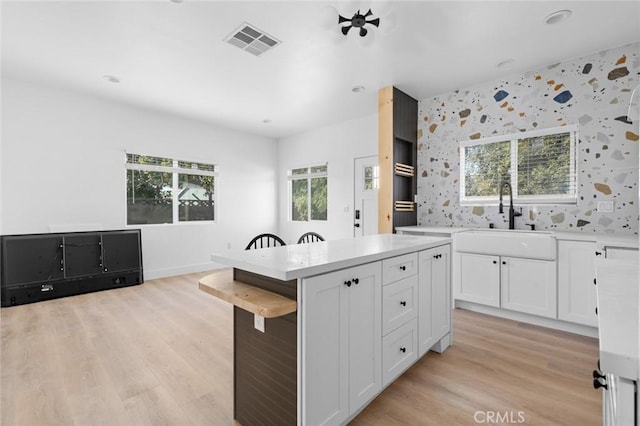 kitchen with a breakfast bar area, a center island, white cabinets, and sink