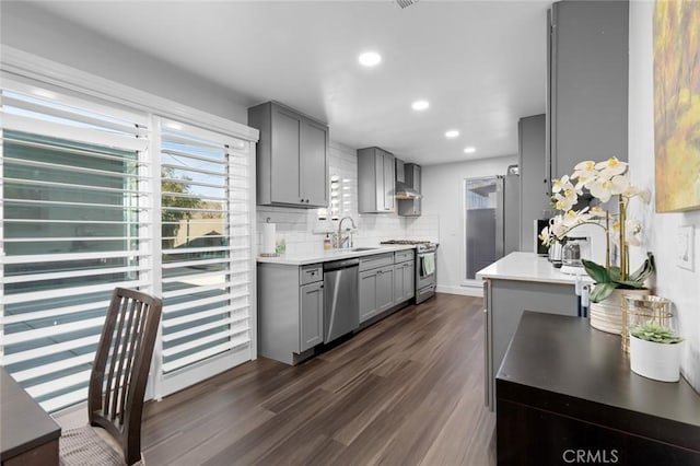 kitchen with gray cabinetry, sink, decorative backsplash, appliances with stainless steel finishes, and dark hardwood / wood-style flooring