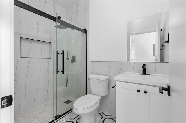 bathroom featuring vanity, toilet, walk in shower, and tile walls