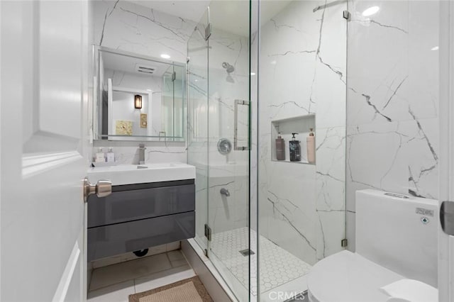 bathroom featuring vanity, a shower with door, tile walls, tile patterned flooring, and toilet