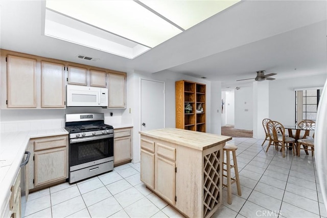 kitchen featuring ceiling fan, light brown cabinets, wood counters, a kitchen island, and appliances with stainless steel finishes