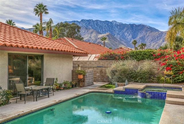 view of swimming pool with a patio area, a mountain view, and an in ground hot tub