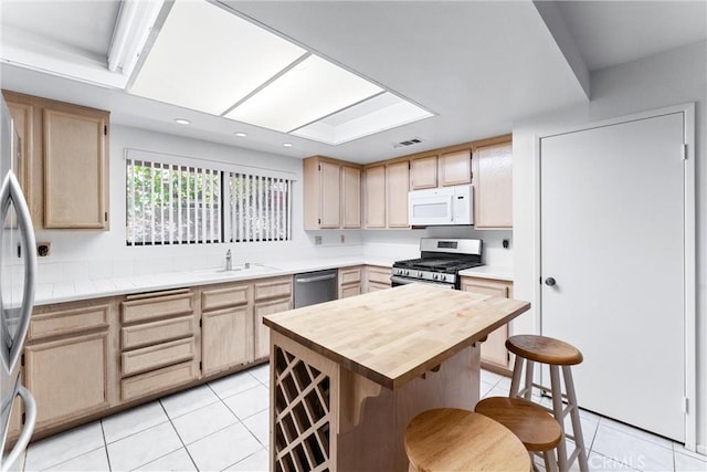 kitchen featuring light tile patterned flooring, light brown cabinetry, and appliances with stainless steel finishes