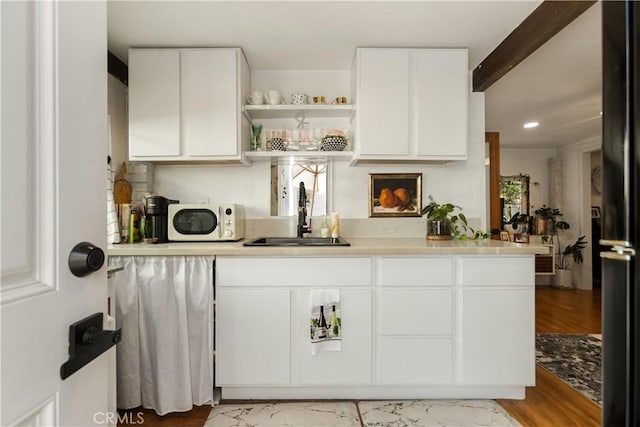 bar with sink, white cabinetry, light hardwood / wood-style flooring, and beam ceiling