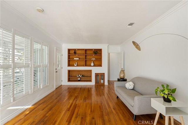 living room featuring wood-type flooring, built in shelves, and ornamental molding