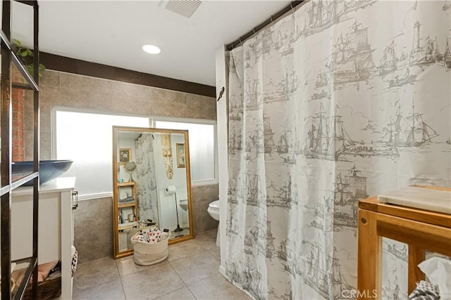 bathroom featuring tile patterned floors, tile walls, toilet, and vanity