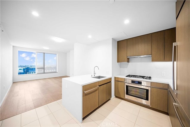 kitchen featuring gas cooktop, kitchen peninsula, stainless steel oven, ventilation hood, and sink