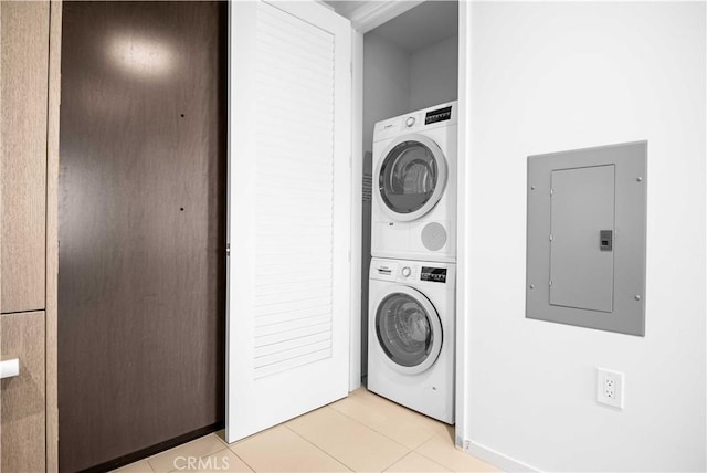 washroom with stacked washing maching and dryer, electric panel, and light tile patterned flooring