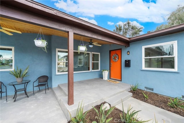 property entrance featuring crawl space, visible vents, a ceiling fan, and stucco siding