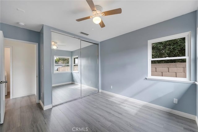 unfurnished bedroom featuring wood-type flooring, a closet, and ceiling fan