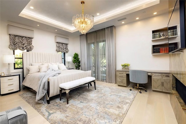 bedroom featuring a raised ceiling, light hardwood / wood-style flooring, built in desk, and a notable chandelier