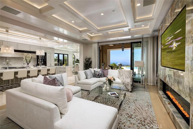 interior space featuring beamed ceiling, light hardwood / wood-style flooring, a tile fireplace, and coffered ceiling