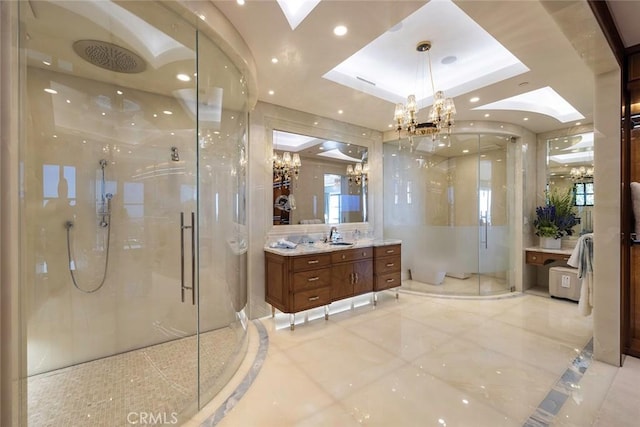 bathroom with vanity, a raised ceiling, a shower with door, and a chandelier