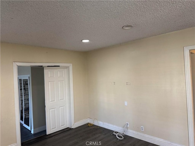 empty room with a textured ceiling and dark hardwood / wood-style flooring