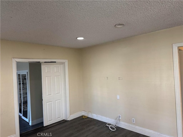 unfurnished room featuring dark wood-style floors, baseboards, and a textured ceiling