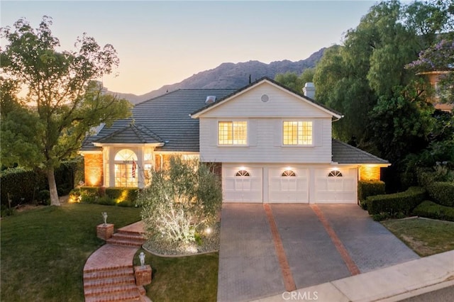 view of front of house with a mountain view, a yard, and a garage