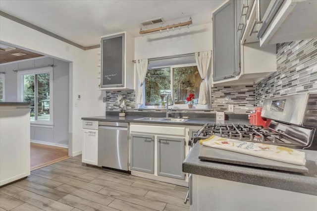 kitchen with stainless steel appliances, light hardwood / wood-style floors, gray cabinets, backsplash, and sink