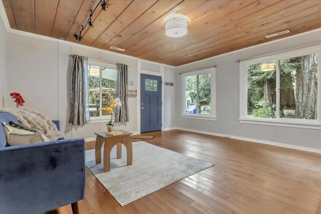 interior space with track lighting, hardwood / wood-style floors, wooden ceiling, and crown molding