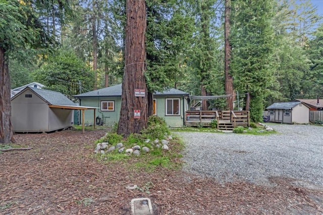 view of front of property featuring a deck and a storage shed