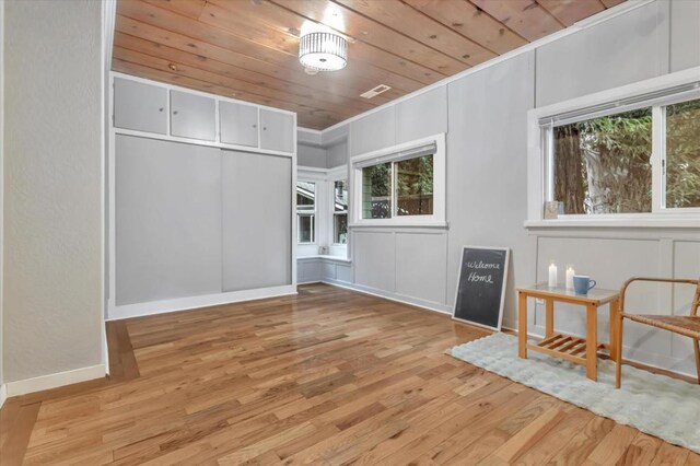 interior space with light hardwood / wood-style floors, crown molding, and wooden ceiling