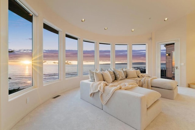 carpeted living room featuring a wealth of natural light, a water view, and lofted ceiling