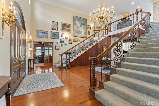 entryway with a high ceiling, hardwood / wood-style flooring, crown molding, and a notable chandelier