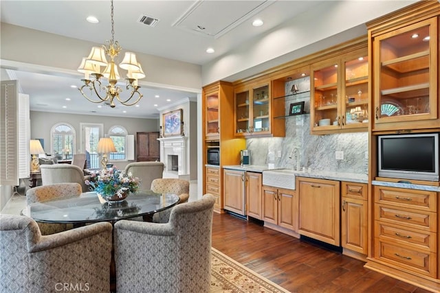 dining area with dark hardwood / wood-style floors, crown molding, sink, and a chandelier