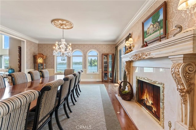 dining space featuring a healthy amount of sunlight, a water view, ornamental molding, and a fireplace