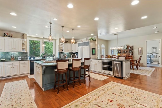 kitchen with white cabinets, pendant lighting, a breakfast bar, and an island with sink