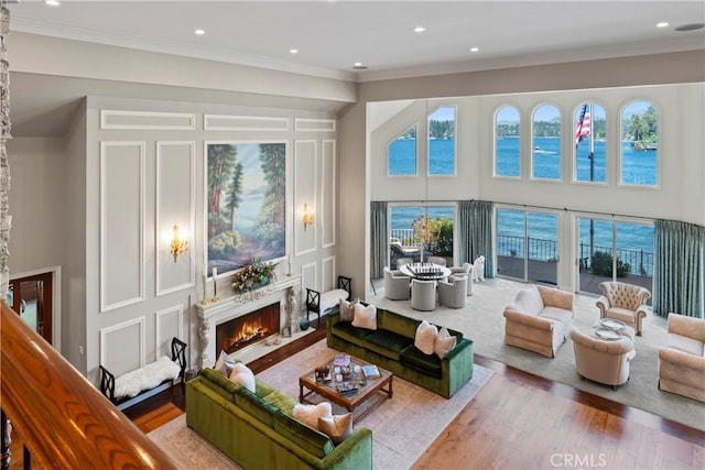 living room featuring a water view, light wood-type flooring, and ornamental molding