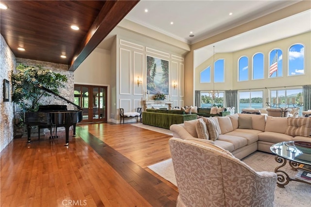 living room featuring a high ceiling, a water view, french doors, and wood-type flooring