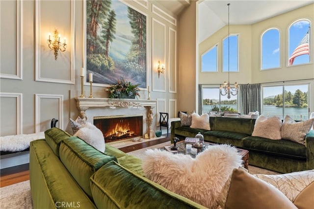 living room featuring a high ceiling, a water view, hardwood / wood-style flooring, and a notable chandelier