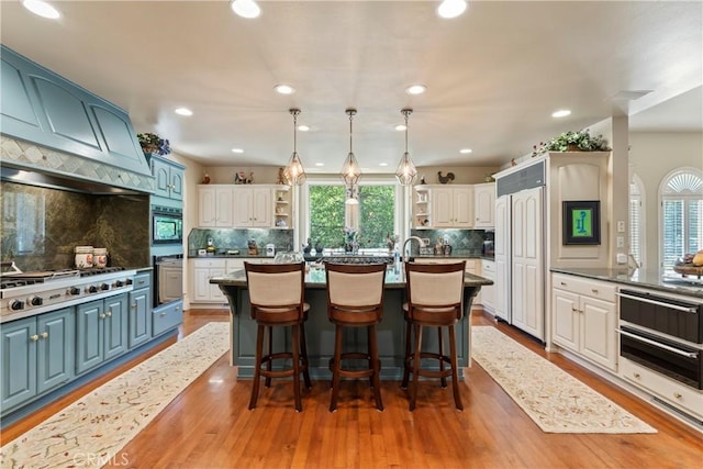 kitchen with decorative backsplash, white cabinetry, and an island with sink