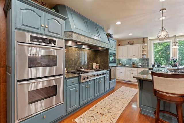 kitchen featuring light hardwood / wood-style flooring, blue cabinetry, appliances with stainless steel finishes, and tasteful backsplash